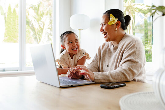 Young girl watching mum attentively while working on her laptop