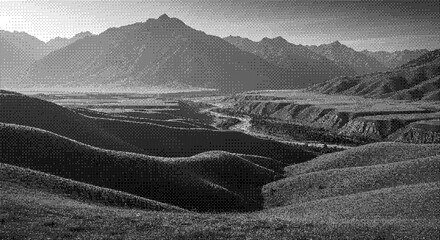 A serene landscape of rolling hills and majestic mountains viewed from a high vantage point in monochrome photography