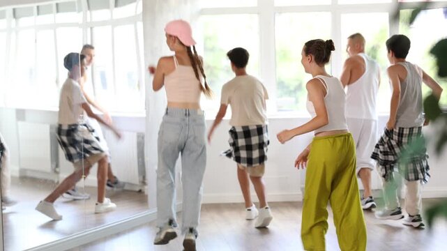 Positive teenage children and young male trainer practicing basic hip-hop steps during group dancing classes. High quality 4k footage