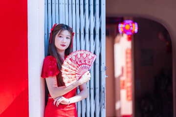 Young woman in red dress holding decorative fan celebrating lunar new year 2026 with traditional style and festive mood