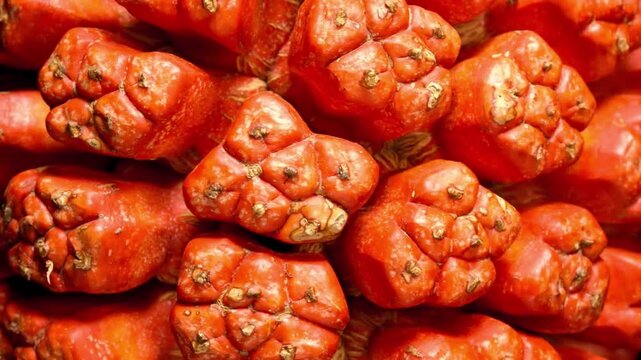 Close-up view of a pile of ripe, textured orange pandanus fruits in a market setting