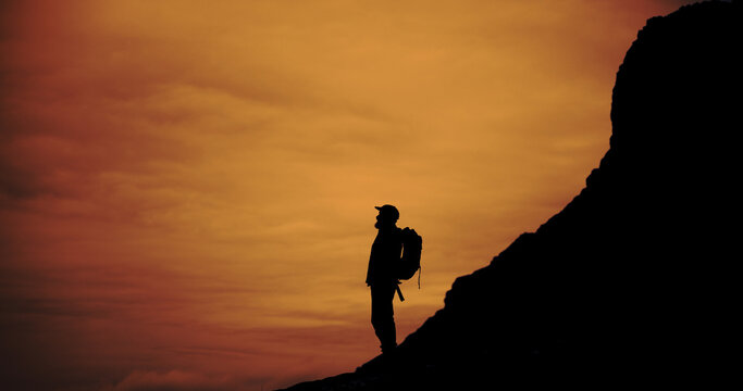Outdoor, trekking and silhouette of man on mountain for adventure, reflection and vacation with view. Holiday, backpacking and person hiking at sunset, travel or thinking with space for sightseeing