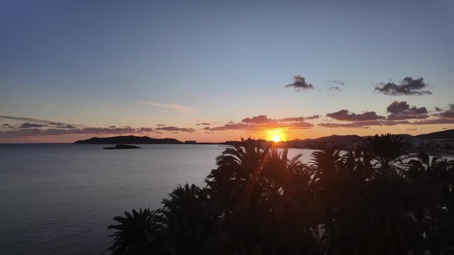 A timelapse of a sunset and nightfall over En Bossa Beach, in Ibiza Island, with scattered low clouds passing over the Mediterranean Sea.