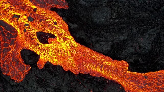 Fiery molten lava flowing over dark volcanic rock, a powerful natural phenomenon