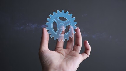 Hand holding a glowing blue holographic gear symbol against a dark, starry background