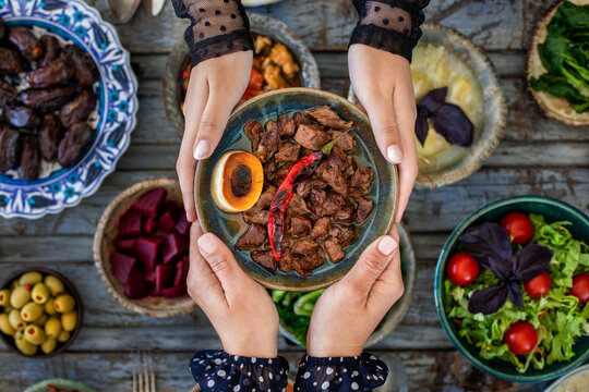 Iftar, break the fasting at holy Ramadan with family, top view of a dining table at iftar time when many human hands sharing their meal. 