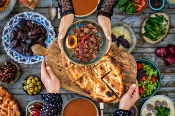 Iftar, break the fasting at holy Ramadan with family, top view of a dining table at iftar time when many human hands sharing their meal. 