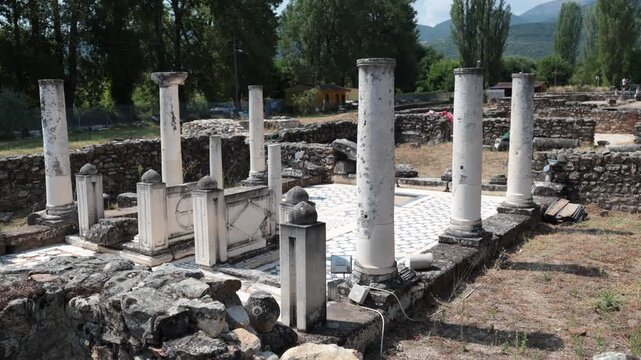 Scenic summer view of archaeological site of Heraclea Lyncestis near Bitola, North Macedonia, overlooking ruins of ancient layered stone walls, marble columns, and surrounding greenery