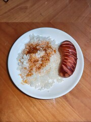 Grilled sausage with rice and sauce on white plate. Simple homemade meal concept for quick dinner. Lunch idea with cooked grain.