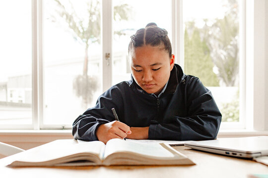Teenage Samoan girl doing her homework on the table