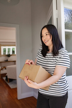 Asian woman holding a package left at the doorstep