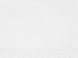 White textured background, close up view of a mineral fiber ceiling tile or acoustic panel surface.