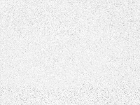 White textured background, close up view of a mineral fiber ceiling tile or acoustic panel surface.