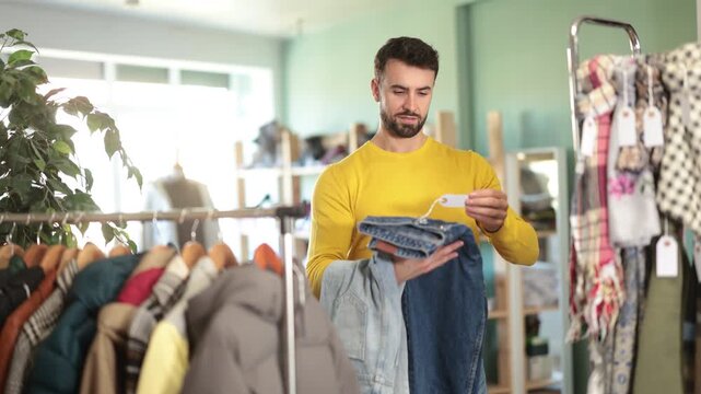 Man spend time in shop and choose jeans. Changing wardrobe, shaping style of clothing. Designer clothes, clothing of world brands. 