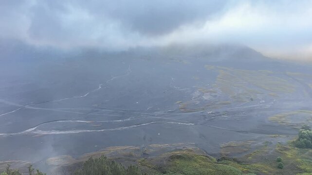 The beautiful scenery of Bromo Valley from the hilltop, shrouded in mist and chilly air, located in the Mount Bromo area of Bromo Tengger Semeru National Park (TNBTS), Wonokitri Village, East Java.