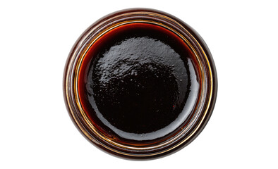 Dark, glossy condiment in a clear glass jar, top-down view