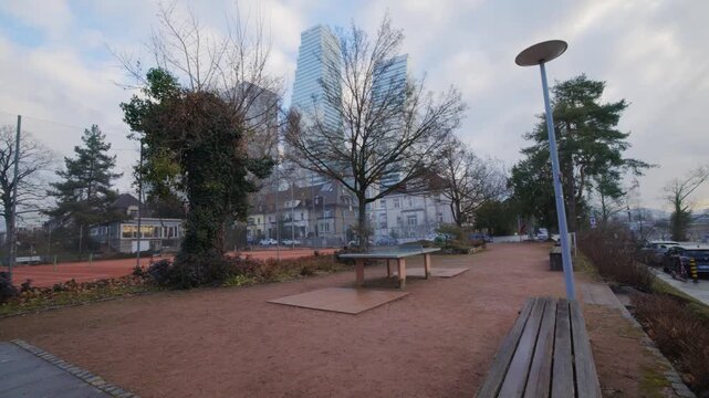 Cinematic pan from a public ping pong table to the Rhine river, Basel city skyline and Roche Towers, Switzerland.