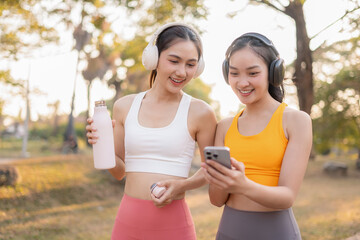 Fototapeta premium Two fit woman using smartphone playing social media after yoga training. lifestyles and healthcare.