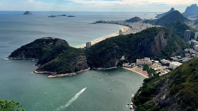 Tilt-up shot starting from the emerald waters of Praia Vermelha and rising to reveal the iconic crescent beaches of Leme and Copacabana along the Rio de Janeiro coast.