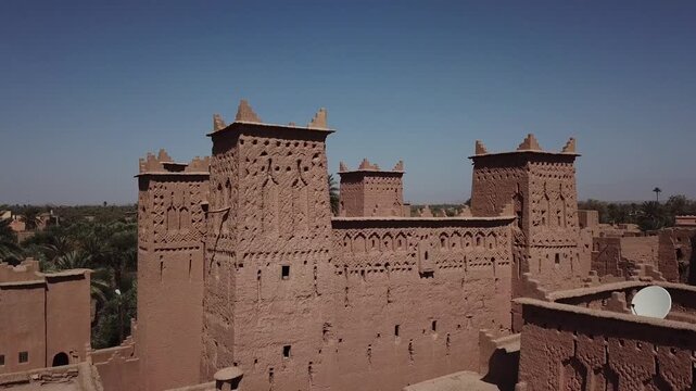 Close-up aerial shot focusing on the traditional Berber geometric patterns and crenellated towers of Kasbah Taourirt. The footage highlights the detailed mud-brick craftsmanship of this historic Moroc