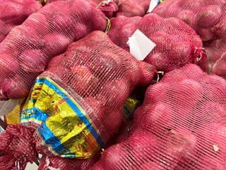 Red onions packed in mesh bags for sale at a grocery or wholesale market. © Akmalism Photography