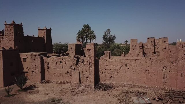 Detail shot of the decaying fortified walls of Kasbah Taourirt in Ouarzazate. The footage captures the rough texture of eroding mud bricks and the historic Berber architecture standing against time.