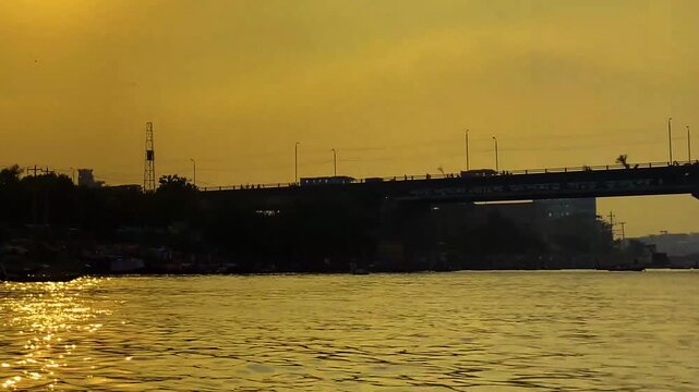 Orange Sunset at Babu Bazar Bridge, Dhaka, with vehicles silhouetted.