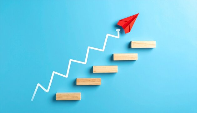 Conceptual image representing progress and aspiration, featuring a white zigzag staircase line on a blue background with five wooden rectangular blocks placed at each step; a red paper airplane positi