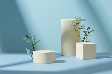 Minimal setup of product podiums and branches on a pastel blue surface, designed for modern product mockups
