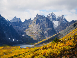 Fototapeta premium Panoramic view of rugged mountains with snow-capped peaks and vibrant autumn foliage in the foreground