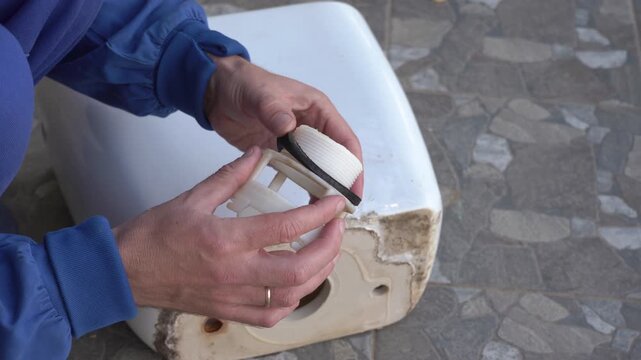 Replacing the sealing gasket of the toilet flush tank, A plumber replaces the rubber gasket that connects the tank with the toilet bowl
