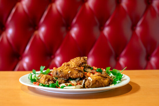 Chicken wings served with garnish against red booth background