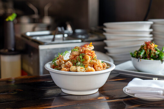 Bowl piled high with calamari restaurant kitchen background