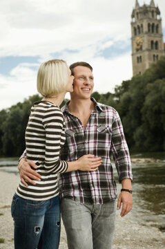 Young couple standing close together on a riverside