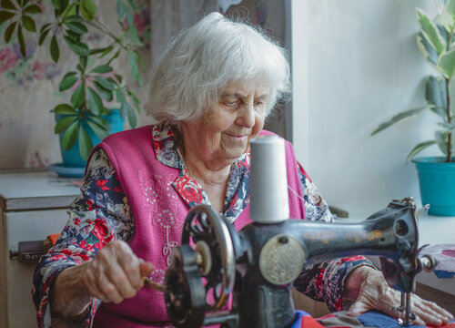 An elderly woman sewing at a sewing machine
