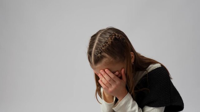 Stressed Young Girl Making Facepalm Gesture.  An expressive young girl covering her eyes with her hand in a facepalm gesture, looking tired or frustrated