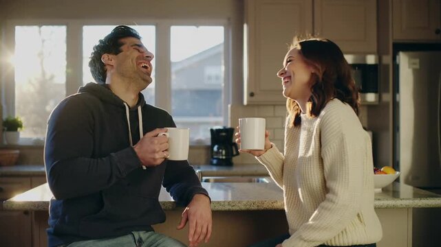 Video of happy couple laughing with coffee in morning conversation having quality time together and making jokes in kitchen.Slow motion.AI Generative.