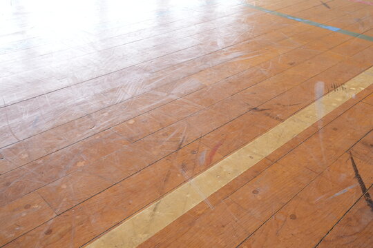 A wooden floor with a white line down the middle. The floor is dirty and has a lot of scuff marks