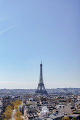 Fototapeta premium Paris skyline in springtime from Arc de Triomphe, sunlit streets and rooftops, distant Eiffel Tower dominating horizon, serene urban panorama in soft sunlight