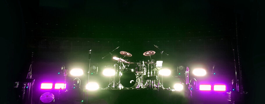 llive music performance in a venue with bright lights and a drum set on stage