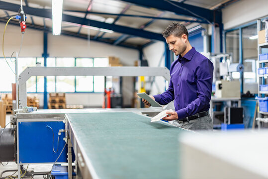 Worker with tablet inspecting production hall in modern industry