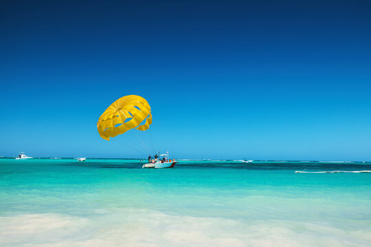 Yellow Parasail Over Turquoise Beach With Boat and Clear Blue Sky Tropical Caribbean vacation