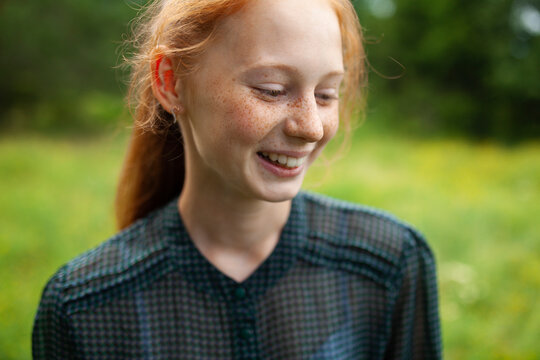 Red-haired freckled young woman smiling outdoors in summer