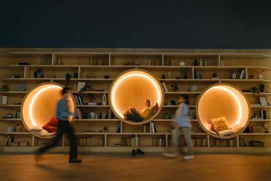 People relaxing and walking in modern library coworking lounge