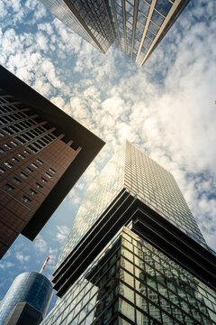 Upward perspective of glass skyscraper against sky in financial urban frankfurt germany emphasizing tall architecture and dramatic city lines