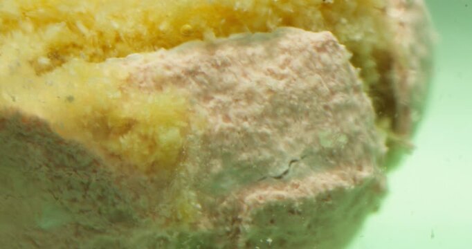 Macro shot of a fizzing bath bomb or chemical reaction in water with soft pastel colors