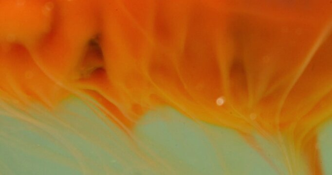 Macro shot of orange bath bomb dissolving in water with fizzing bubbles and organic fluid motion
