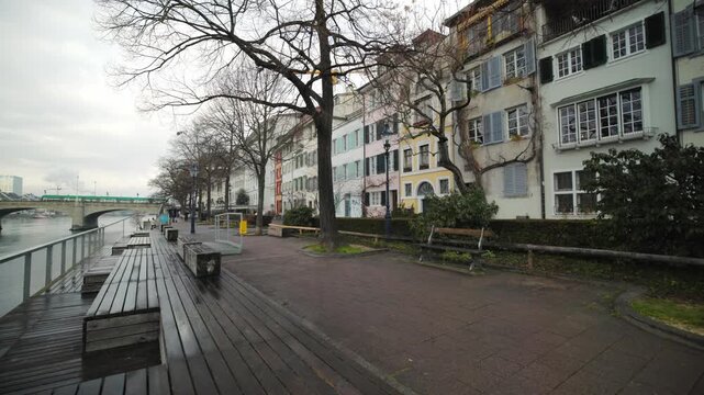 Cinematic pan of traditional historic houses and wooden walkways along the Rhine river in Basel, Switzerland.