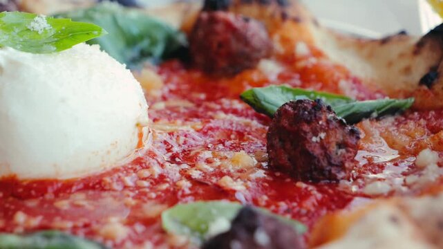 Delicious pizza with meatballs, stracciatella, and burrata, topped with basil and tomato sauce. Italian cuisine concept.