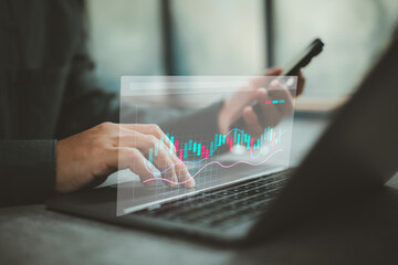 Businessperson analyzing stock market data on laptop with smartphone technology